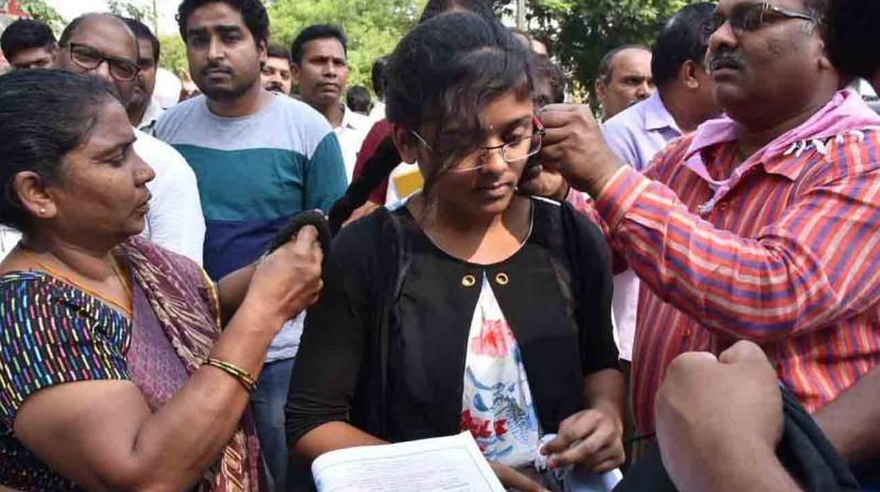 Family members remove earrings of a Neet aspirant before she enters the exam hall on Sunday. (Photo: DC) Family members remove earrings of a Neet aspirant before she enters the exam hall on Sunday. (Photo: DC)