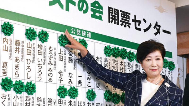 Tokyo Gov. Yuriko Koike smiles as she adds another green rosette on the name of an elected candidate of her new party, Tomin First no Kai, or Tokyoites First Party, while waiting for the result of Sunday's city assembly election in Tokyo. (Photo: AP) Tokyo Gov. Yuriko Koike smiles as she adds another green rosette on the name of an elected candidate of her new party, Tomin First no Kai, or Tokyoites First Party, while waiting for the result of Sunday's city assembly election in Tokyo. (Photo: AP)