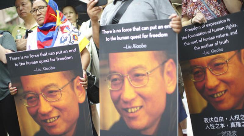 Participants, one wearing a Tibetan flag, hold photos of Liu Xiaobo during a vigil honoring Xiaobo's legacy and to protest continued human rights abuses in China. (Photo: AP) Participants, one wearing a Tibetan flag, hold photos of Liu Xiaobo during a vigil honoring Xiaobo's legacy and to protest continued human rights abuses in China. (Photo: AP)