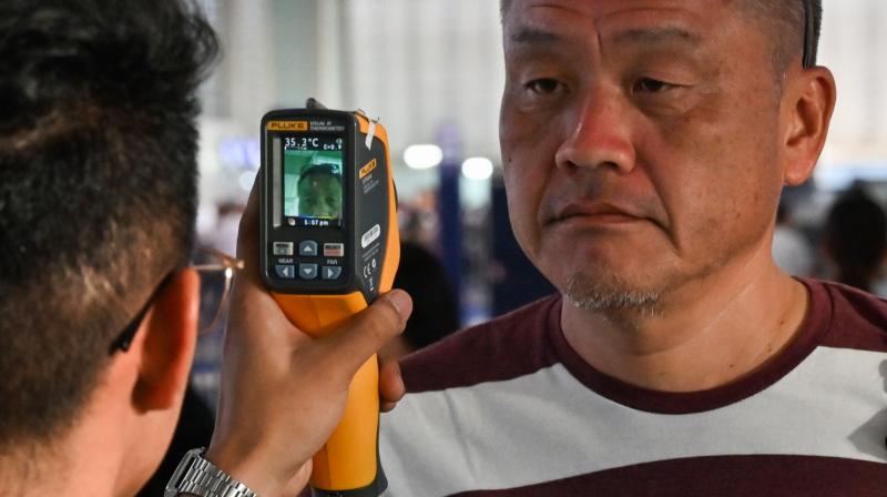 Airport personnel check the temperature of a passenger at the departure area of the international airport in Manila. AFP Photo