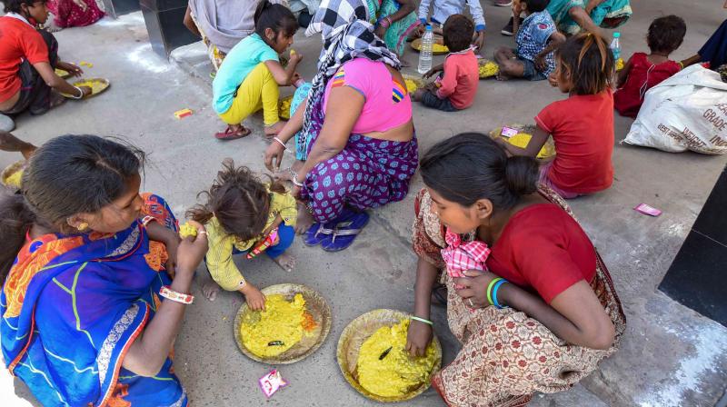 Homeless people consume meals, distributed by RPF personnel, during a nationwide lockdown in the wake of coronavirus pandemic, in Patna on Sunday. PTI image