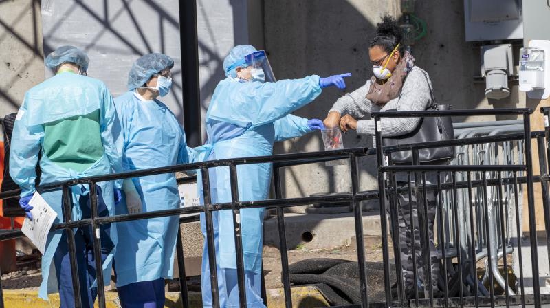 A member of the Brooklyn Hospital Center helps a person who was just tested for COVID-19 put an object in a biohazard bag in New York. AP Photo.