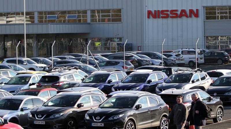 Workers leave the Nissan car plant after finishing their shift. ()