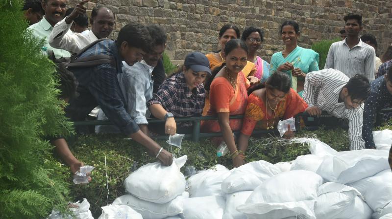 People collecting drinking water packets packed in single-use plastic which was arranged by HMWSSB at Golkonda. (DC Image)