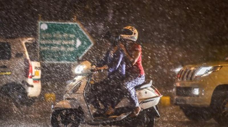 Commuters ride on a scooter during a thunderstorm in New Delhi on Wednesday. Change in the weather has brought respite in parts of Delhi and the National Capital Region (NCR) reeling under warm weather conditions for past days. (Photo: PTI) Commuters ride on a scooter during a thunderstorm in New Delhi on Wednesday. Change in the weather has brought respite in parts of Delhi and the National Capital Region (NCR) reeling under warm weather conditions for past days. (Photo: PTI)