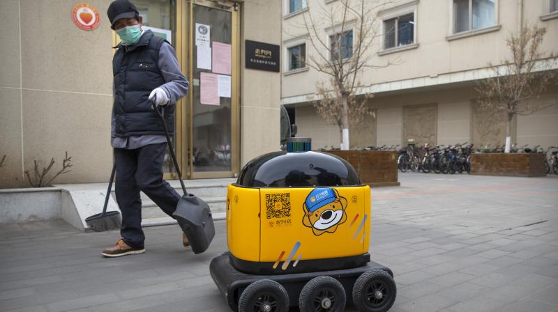 In this March 18, 2020, photo, a maintenance worker looks at a robot outside the offices of ZhenRobotics in Beijing. (Photo | AP) In this March 18, 2020, photo, a maintenance worker looks at a robot outside the offices of ZhenRobotics in Beijing. (Photo | AP)