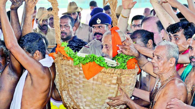 Devotees take part in the funeral procession of Swami Vishvesha Teertha in Mangaluru on Sunday. The 88-year old seer, one of the prominent religious leaders of South India, died after a brief illness.    (PTI)