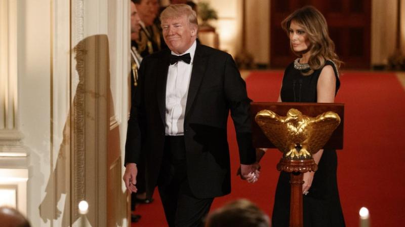 President Donald Trump holds hands with first lady Melania Trump as they take their seats after he spoke at the Governors Ball on Sunday in the East Room of the White House in Washington. AP photo