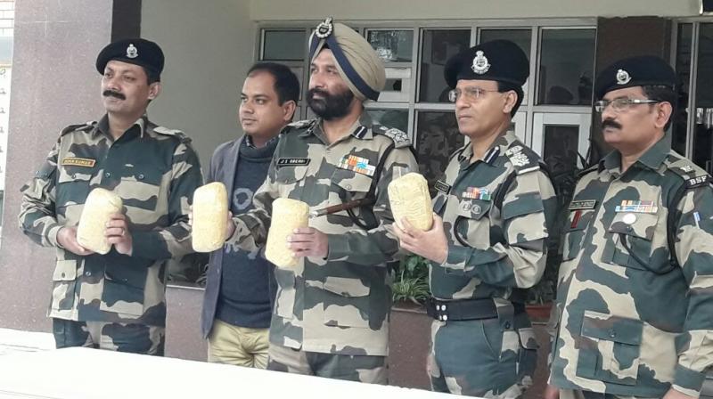 Officers hold the packets of heroin found around the border fence. (Photo: Twitter | @BSF_India) Officers hold the packets of heroin found around the border fence. (Photo: Twitter | @BSF_India)