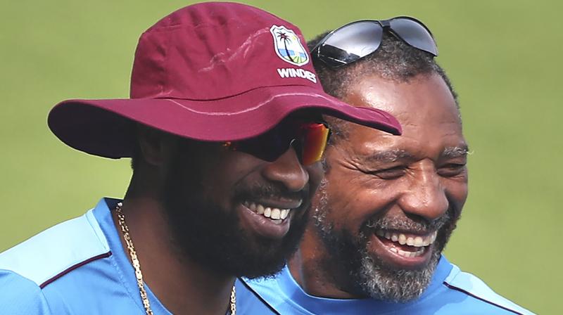 West Indies captain Kieron Pollard (L) shares a light moment with head coach Phil Simmons. AP Photo