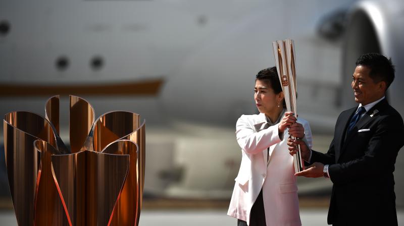 Japanese three-time Olympic gold medallists Saori Yoshida (L) and Tadahiro Nomura hold the Tokyo 2020 olympic torch, after transporting the flame from Greece, at the Japan Air Self-Defense Force Matsushima Base in Higashimatsushima, Miyagi prefecture. AFP Photo