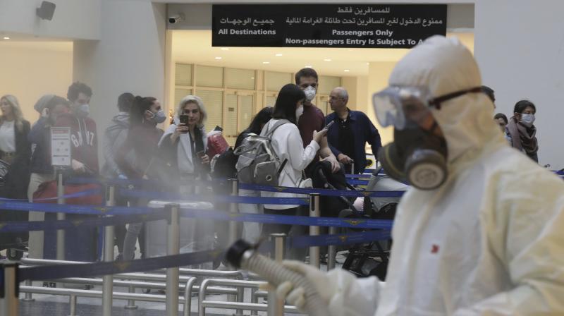 Workers wear masks and spray disinfectant at the Beirut airport on Thursday. AP Photo