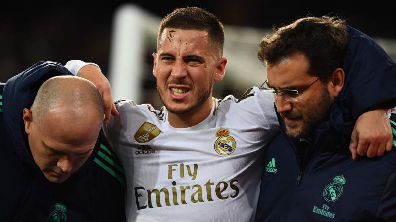 In this file photo taken on November 26, 2019, Eden Hazard grimaces in pain while he was being helped out of the field during the UEFA Champions League group A match against Paris Saint-Germain at the Santiago Bernotoabeu stadium in Madrid. AFP Pha fracture in his right ankle, Real Madrid confirmed on December 5, 2019. (Photo by GABRIEL BOUYS / AFP)