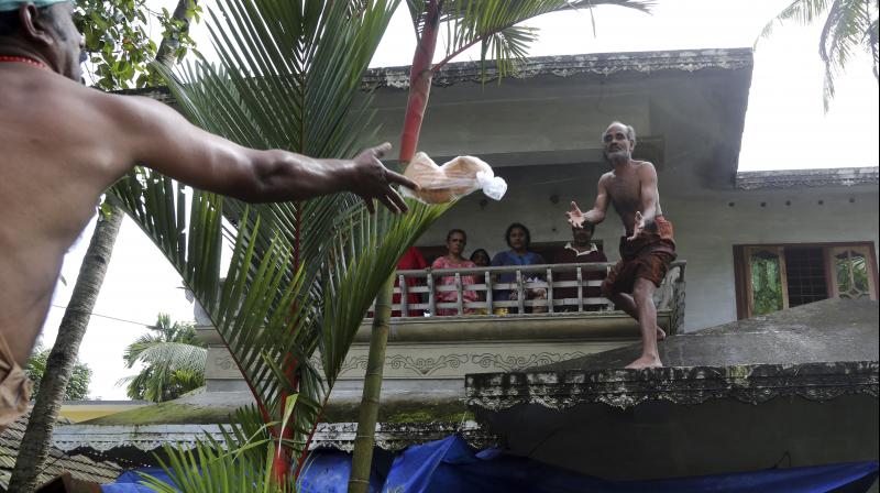 A volunteer throws a pack of bread towards a family stranded in a flooded area in Chengannur. (Photo: PTI) A volunteer throws a pack of bread towards a family stranded in a flooded area in Chengannur. (Photo: PTI)
