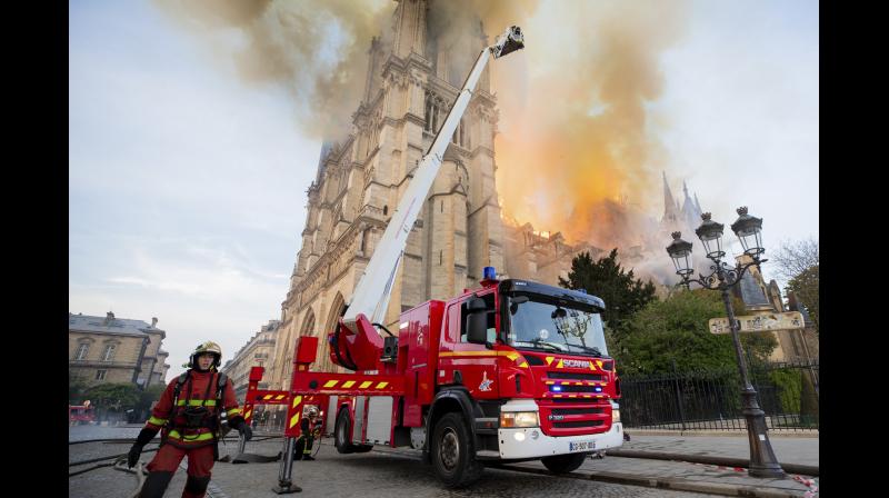Paris Fire Brigade shows fire fighters working at the burning Notre Dame cathedral. (Photo:AP) Paris Fire Brigade shows fire fighters working at the burning Notre Dame cathedral. (Photo:AP)