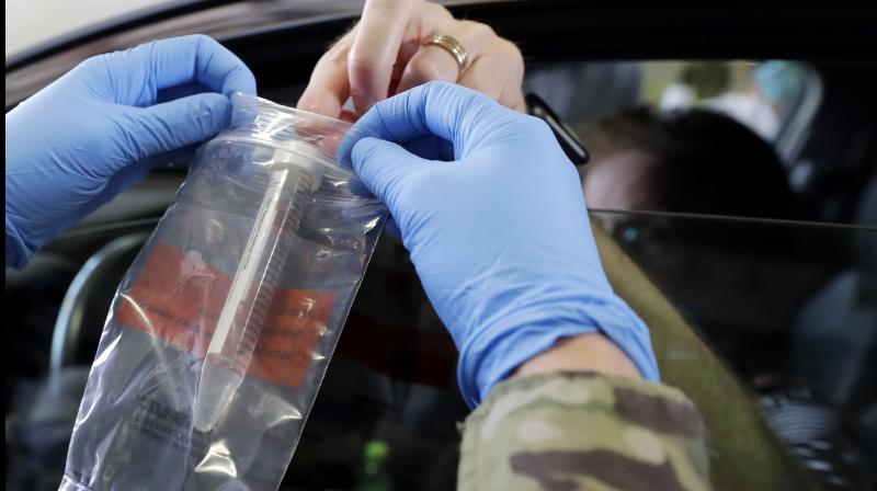 Passenger hands over his testing kit to Illinois National Guard soldier Carlye Clehouse at a testing facility in Waukegan. (AP)