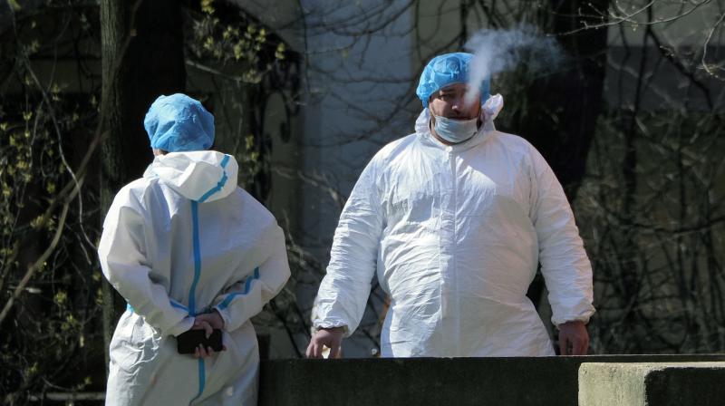 A medical worker wearing protective equipment to protect against coronavirus smokes as he and his colleague rest in the yard of the Pokrovskaya hospital in St.Petersburg, Russia. (AP)