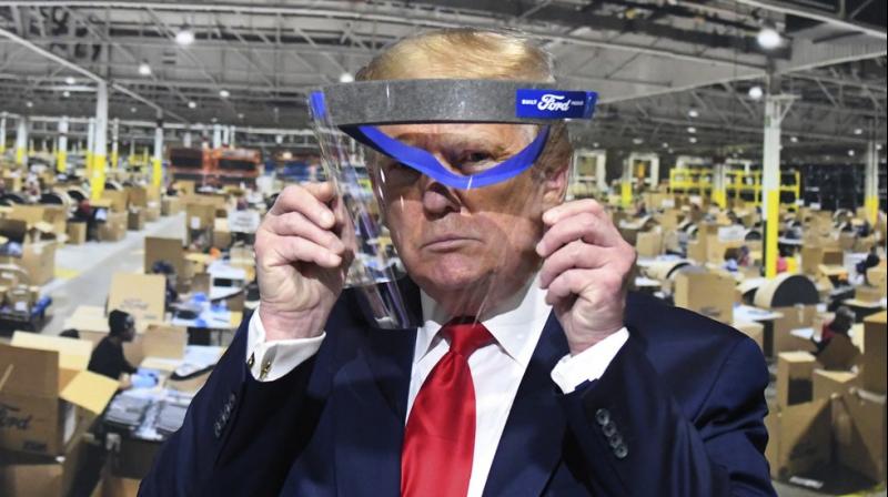 President Donald Trump looks through a face shield, in front of poster of the manufacturing of these shields, while touring Ford Motor Co.s Rawsonville Components Plant in Ypsilanti, Michigan. (AP)