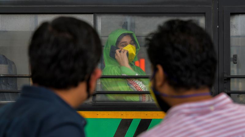 A woman (C) speaks on her phone on a bus before being taken to a quarantine facility after arriving from Mumbai. (AFP)