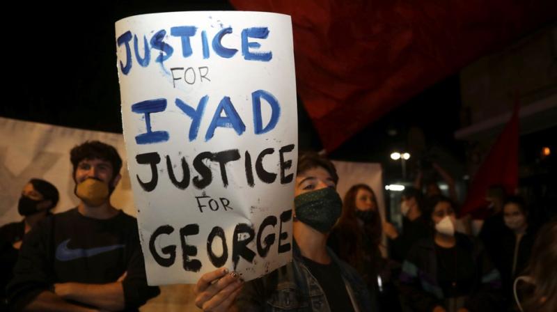 Protesters hold signs against the Israeli police after they shoot dead an unarmed autistic Palestinian man Iyad Halak in Jerusalems Old City on Saturday after saying they suspected he was carrying a weapon. (AP)