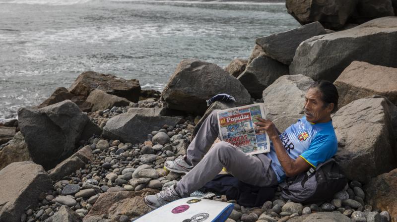 A man reads a newspaper next to the Pacific Ocean on the coast of Lima, Peru. (AP) A man reads a newspaper next to the Pacific Ocean on the coast of Lima, Peru. (AP)