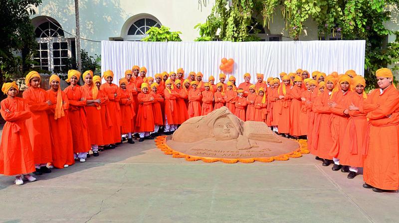 Children dressed as Swamy Vivekananda stand around the sand sculpture on the 155th birth anniversary celebrations at Sri Prakash School in Visakhapatnam on Friday