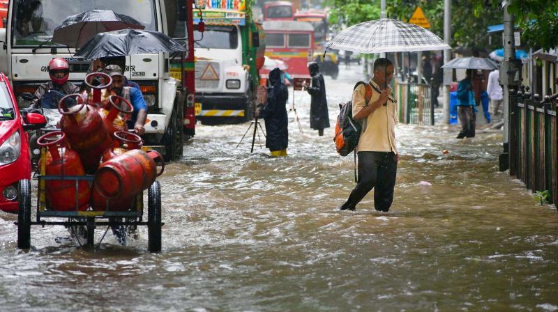 Commuters wade through a waterlogged road following Monsoon rains, in Mumbai, Tuesday, July 5, 2022. The IMD, Tuesday issued a heavy rainfall alert for Maharashtra over the next four days. (PTI Photo)