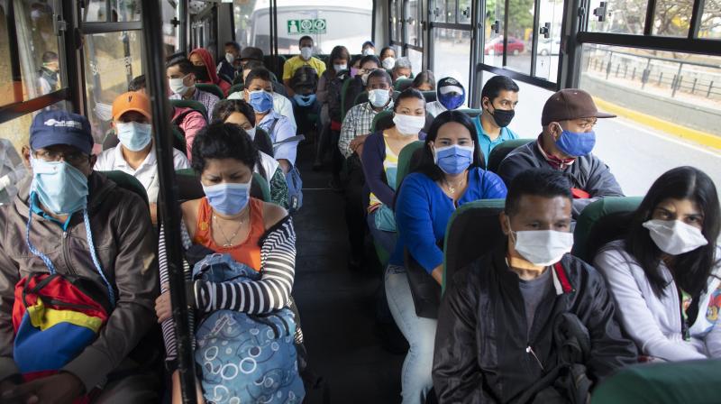 People wearing protective masks as a precaution against the spread of the new coronavirus travel on a bus in Caracas, Venezuela. AP Photo