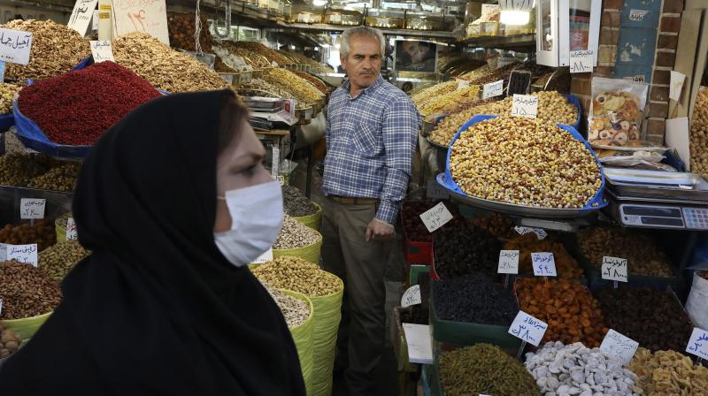 A shopkeeper waits for customers as a woman wearing a face mask to help protect against the new coronavirus, walks at the Tehrans Grand Bazaar, Iran. AFP Photo