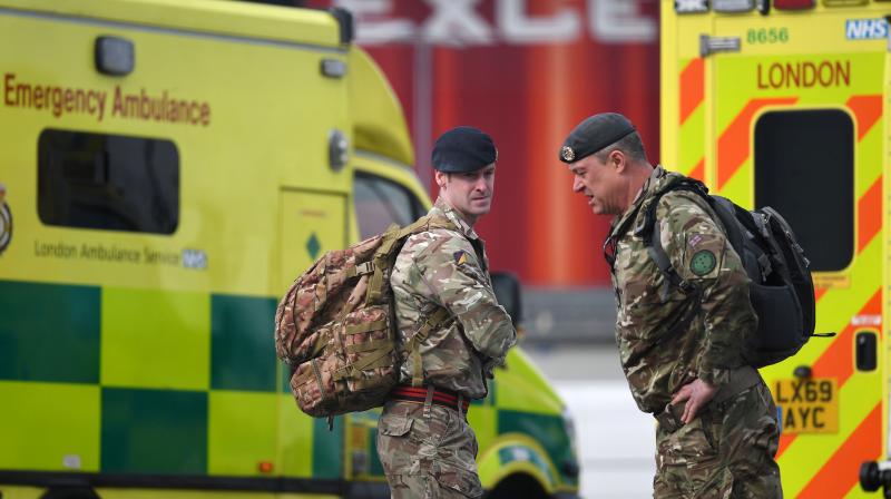 Members of Britains armed forces stand by London Ambulances in a car park at the ExCeL London exhibition centre in London. AFP Photo