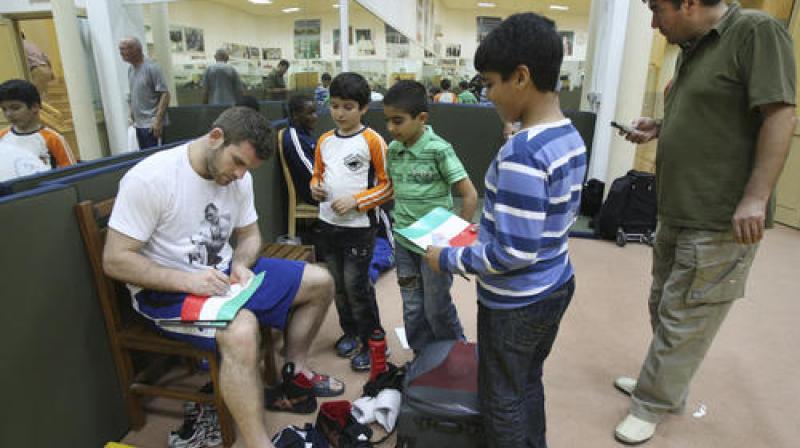 U.S. free style wrestler Daniel Bergman, left, signs Iranian flags for Iranian boys during Takhti Wrestling Cup, on the Persian Gulf island of Kish, Iran. (Photo: AP) U.S. free style wrestler Daniel Bergman, left, signs Iranian flags for Iranian boys during Takhti Wrestling Cup, on the Persian Gulf island of Kish, Iran. (Photo: AP)