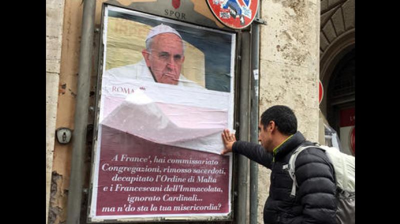 A passerby lifts a paper sheet covering an anti-Pope Francis poster to read it, in central Rome. (Photo: AP) A passerby lifts a paper sheet covering an anti-Pope Francis poster to read it, in central Rome. (Photo: AP)