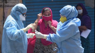 Doctors wearing protective suits examine a woman in a bid to detect COVID-19 positive cases, at a camp at Sewri slums during the nationwide lockdown, in Mumbai. PTI Photo