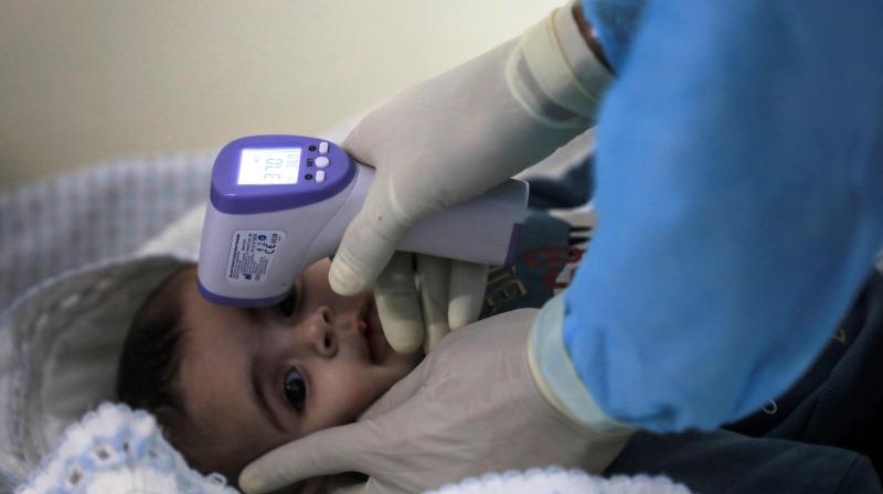 A Palestinian health workers check the temperatire of a child in Gaza city. AFP Photo