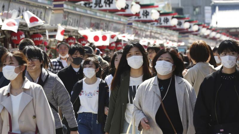 Visitors wearing face masks walk through Nakamise alley at Asakusa in Tokyo. AP Photo