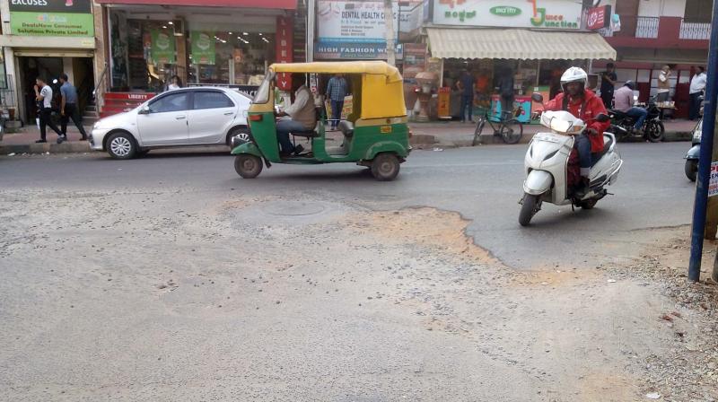 A two-wheeler rider tries to manoeuvre around big potholes in Koramangala 6th Block. (DC) A two-wheeler rider tries to manoeuvre around big potholes in Koramangala 6th Block. (DC)