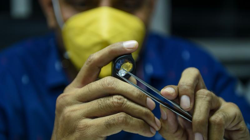 A worker examines diamond stones at Rijiya Gems, a diamond cutting and polishing workshop. (AFP Photo)