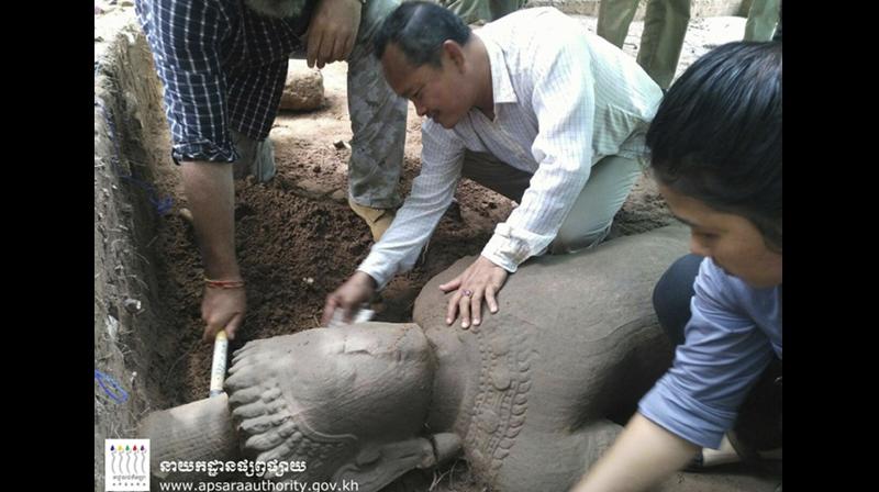 In this July 30, 2017, image made available by the Apsara Authority of the Cambodian Government, archaeologists examine a 1.9-meter (6-foot, 3-inch) tall, 58-centimeter (23-inch) wide statue at Angkor Wat in Siem Reap, Cambodia. Working with experts from Singapore's Institute of Southeast Asian Studies, the Apsara Authority said the 12th or 13th century statue is one of the largest to be unearthed in recent years. (Apsara Authority via AP) In this July 30, 2017, image made available by the Apsara Authority of the Cambodian Government, archaeologists examine a 1.9-meter (6-foot, 3-inch) tall, 58-centimeter (23-inch) wide statue at Angkor Wat in Siem Reap, Cambodia. Working with experts from Singapore's Institute of Southeast Asian Studies, the Apsara Authority said the 12th or 13th century statue is one of the largest to be unearthed in recent years. (Apsara Authority via AP)