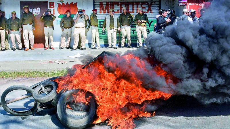 Police personnel look on as tyres are seen ablaze during a strike called by All Assam Students' Union and the North East Students’ Organisation in protest against Citizenship (Amendment) Bill, 2016, in Dibrugarh. (PTI) Police personnel look on as tyres are seen ablaze during a strike called by All Assam Students' Union and the North East Students’ Organisation in protest against Citizenship (Amendment) Bill, 2016, in Dibrugarh. (PTI)