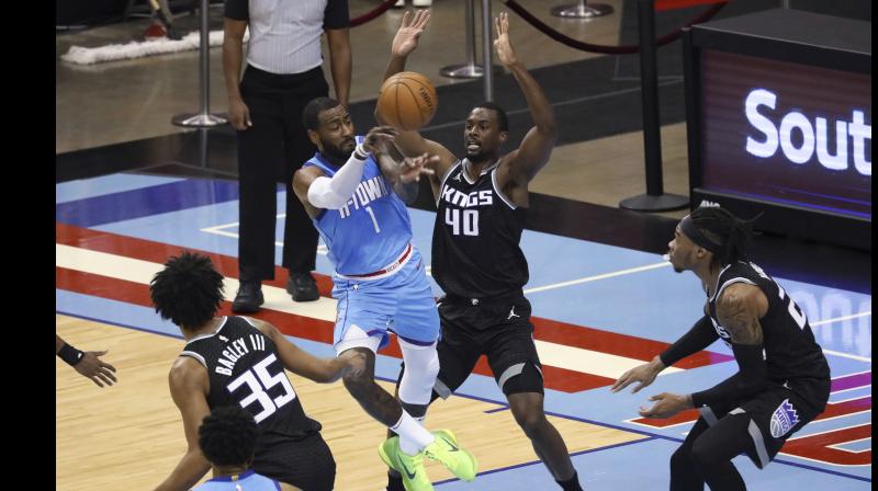 John Wall (second from left) of Houston Rockets passes the ball around Harrison Barnes of Sacramento Kings during their NBA game in Houston on Thursday. 	 AP