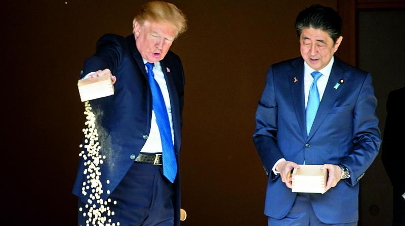 US President Donald Trump and Japanese PM Shinzo Abe feed koi fish during a welcoming ceremony in Tokyo on Monday. (Photo: AFP) US President Donald Trump and Japanese PM Shinzo Abe feed koi fish during a welcoming ceremony in Tokyo on Monday. (Photo: AFP)