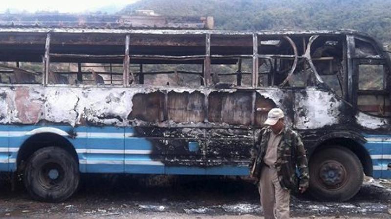 Police personnel walks infront of a charred bus burnt down by bandh supporters of United Naga Council, at Senapati, Manipur. (Photo: PTI) Police personnel walks infront of a charred bus burnt down by bandh supporters of United Naga Council, at Senapati, Manipur. (Photo: PTI)