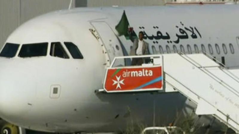 An Afriqiyah Airways plane stands on the tarmac at Malta International airport as an unidentified man waves a flag. (Photo: AP) An Afriqiyah Airways plane stands on the tarmac at Malta International airport as an unidentified man waves a flag. (Photo: AP)
