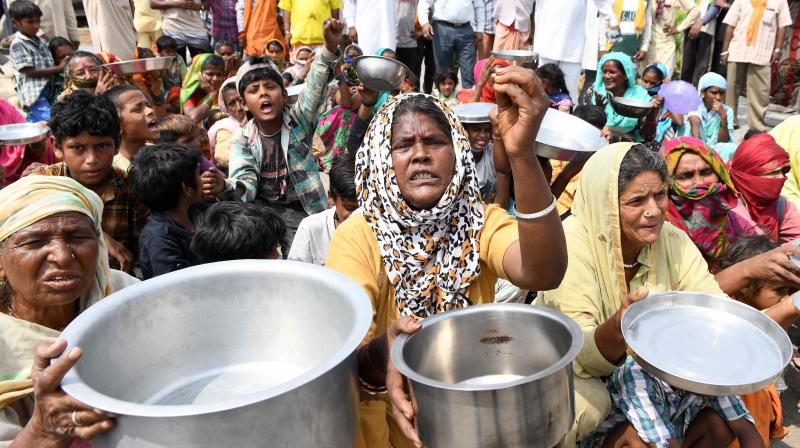 Guest workers and their family members from Maharastra hold kitchen utensils as they protest against the government for the lack of food in a slum area, after the government eased a nationwide lockdown imposed as a preventive measure against the COVID-19 coronavirus, on the outskirts of Amritsar. PTI Photo