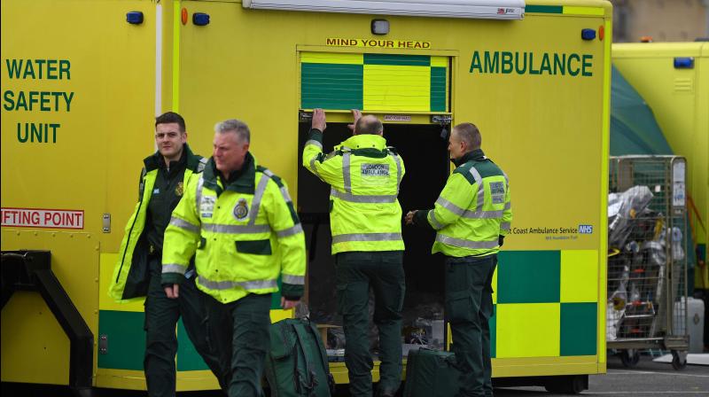 London Ambulance staff walk past amblulances parked in the car park at the ExCeL London exhibition centre in London on March 29, 2020, which has been transformed into a field hospital to be known as the NHS Nightingale Hospital, to help with the novel coronavirus COVID-19 pandemic. (Photo | AFP)