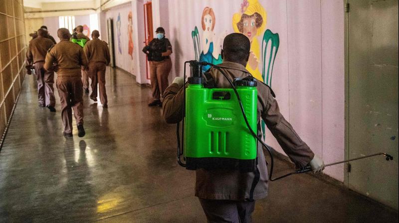 A security guard sanitises the area around a correctional centre in South Africa. AFP photo