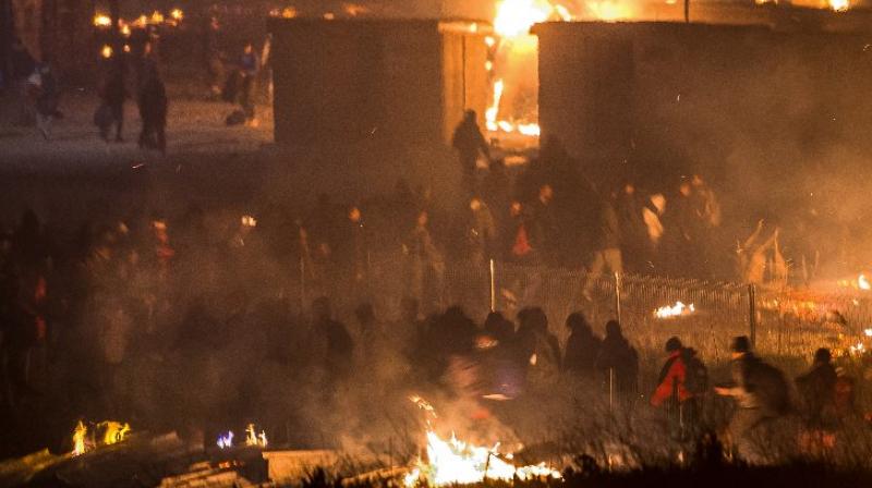 Migrants evacuate a camp of closely-packed wooden huts at Grande-Synthe near Dunkirk, as a huge fire reduces it to ashes (Photo: AFP) Migrants evacuate a camp of closely-packed wooden huts at Grande-Synthe near Dunkirk, as a huge fire reduces it to ashes (Photo: AFP)