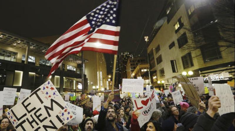 A protester waves a US flag as another holds a sign that reads "Let Them In" during a march and rally to oppose President Donald Trump's executive order barring people from certain Muslim nations from entering the United States in Seattle. (Photo: AP) A protester waves a US flag as another holds a sign that reads "Let Them In" during a march and rally to oppose President Donald Trump's executive order barring people from certain Muslim nations from entering the United States in Seattle. (Photo: AP)