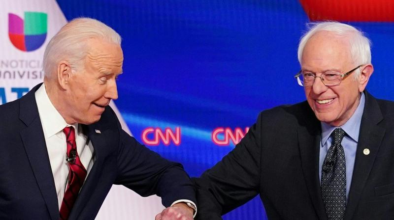 Joe Biden (left) and Bernie Sanders greet each other with a safe elbow bump before a Democratic Party presidential debate in Washington on March 15, 2020. Sanders has suspended his presidential campaign, clearing the way for rival Joe Biden to become the Democratic nominee to challenge Donald Trump in November. (AFP)