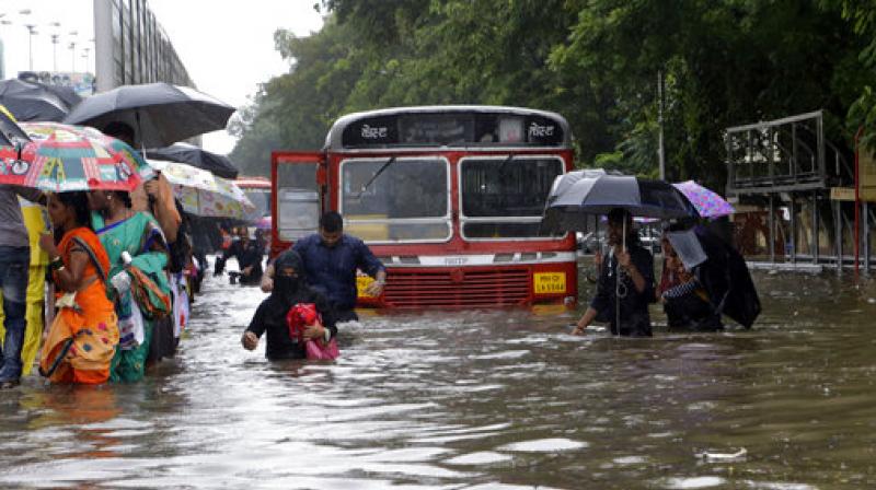 People walk through a waterlogged street following heavy rains in Mumbai. (Photo: AP) People walk through a waterlogged street following heavy rains in Mumbai. (Photo: AP)
